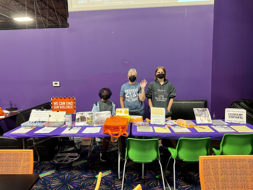 Three women behind a table covered in gun violence prevention information.