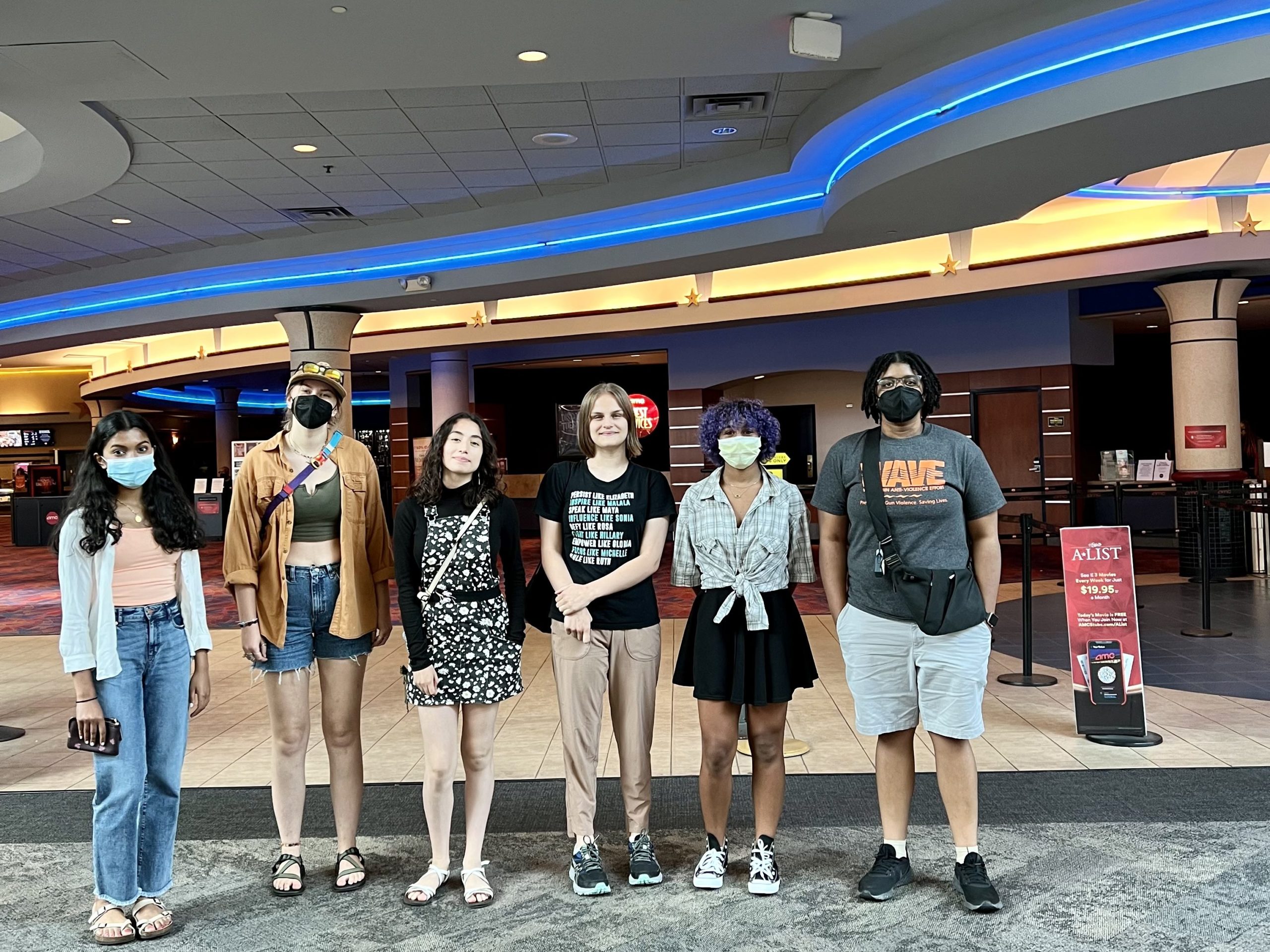 Image of six young women standing in front of a movie theater